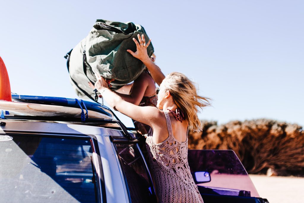Top 10 Must-Have Accessories for Your 4x4 Adventure a woman placing a large bag on roof rack